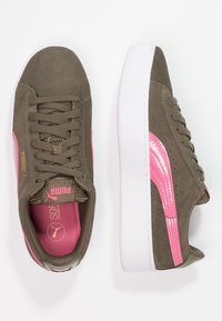 Zamszowe tenisówki w oliwkowo-zielonym kolorze z różowym błyszczącym paskiem, białą gumową podeszwą i różową podszewką w środku. Posiadają płaskie sznurowadła oraz wytłoczone logo.