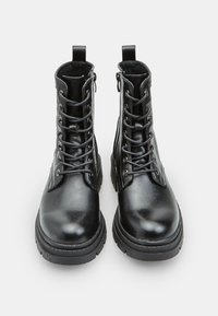 Stivali alla caviglia in pelle nera con una texture liscia, allacciatura frontale, linguette per il tallone e suole in gomma durevoli. Presentano delle cuciture decorative.