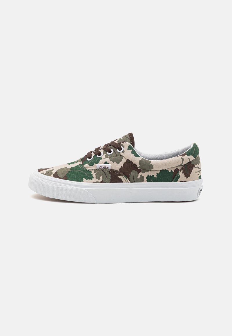 Baskets basses Vans avec motif camouflage vert, marron et beige, semelle en caoutchouc blanc et lacets marron foncé sur fond uni.