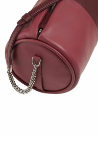 Borsa rotonda in pelle bordeaux con zip superiore, una tracolla in pelle e un accento in catena argento alla base. Texture liscia e design minimal.