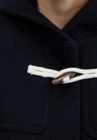 Cappotto navy con chiusura a toggle che presenta un bottone marrone, dettagli in corda bianca e tasche a toppa sul petto. Texture morbida in lana.