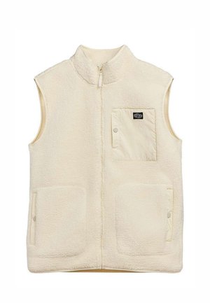 Veste sans manches en polaire crème avec fermeture éclair à l'avant, deux poches plaquées basses avec boutons-pression, et une poche poitrine avec bouton-pression et patch logo noir.