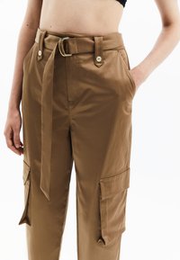 Donkerbruine cargobroek met een hoge taille, grote zijzakken, een ceintuur met een gouden gesp en een soepele stofafwerking.