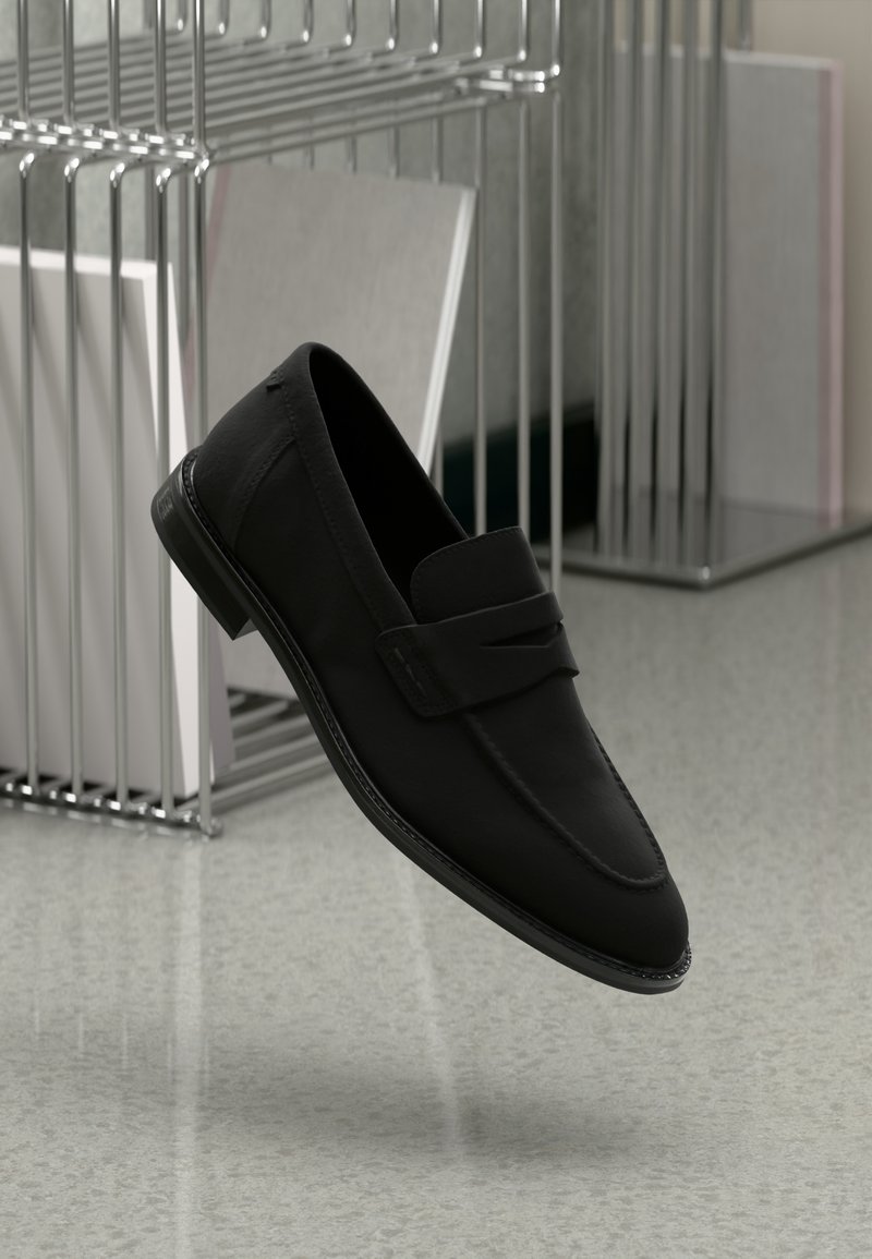 Svarta loafers i slätt läder, med en subtil remdetalj och rund tå. Sulan är strömlinjeformad med en minimalistisk kantdesign.
