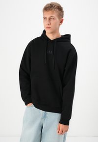 Black hooded sweatshirt with a front pocket and a subtle "GAP" logo. Made from soft fabric with ribbed cuffs and a relaxed fit.