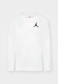 Pitkähihainen valkoinen puuvillainen t-paita, jossa vasemmassa rinnassa musta Jumpman-logo ja resorinen pyöreä pääntie. Sileä tekstuuri.