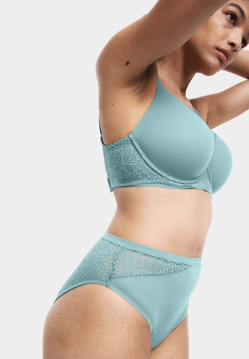 Bh met kant in petrolblauw en gladde stof, gecombineerd met een slip met hoge taille. De bh heeft kanten zijpanelen, een naadloos ontwerp en verstelbare bandjes.