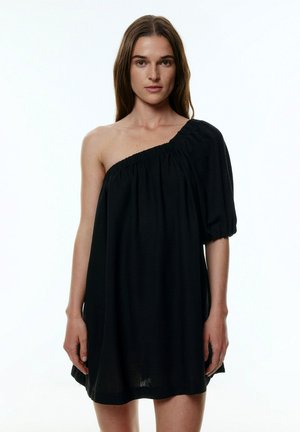 Zwarte, one-shoulder jurk met een pofmouw en een gathered halslijn. Zacht, gestructureerd materiaal met een losse, comfortabele pasvorm.