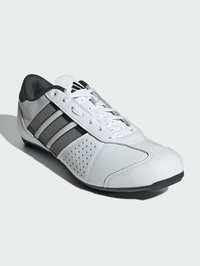 Białe buty sportowe z czarnymi akcentami, z gładką skórzaną cholewką, siateczkowymi detalami, otworami dla lepszej wentylacji i czarną gumową podeszwą.