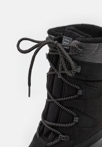 Schwarze Winterstiefel mit Obermaterial aus Textil und gesteppte Akzente, kontrastierenden grauen Bündchen und schwarz-weißen Schnürsenkeln.