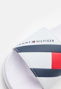 Sandalo a fascia con una parte superiore in sintetico bianco e strisce blu e rosse. Logo "TOMMY HILFIGER" stampato vicino alla cinghia, suola texturizzata.