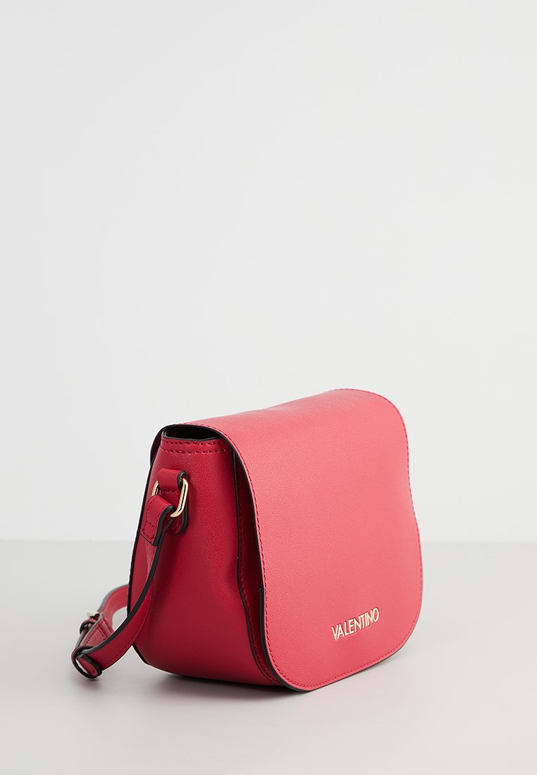 Sac bandoulière en cuir rouge avec une fermeture à rabat, accents en métal doré et surface texturée. Comprend une sangle ajustable et un détail de logo.