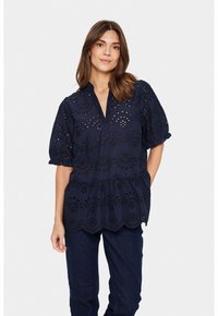 Marineblaue Bluse mit Durchbrüchen, kurzen Puffärmeln und gewelltem Saum. Mit einem V-Ausschnitt und geraffter Taille für eine lockere Passform.