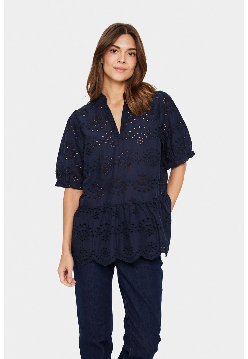 Marineblaue Bluse mit Durchbrüchen, kurzen Puffärmeln und gewelltem Saum. Mit einem V-Ausschnitt und geraffter Taille für eine lockere Passform.