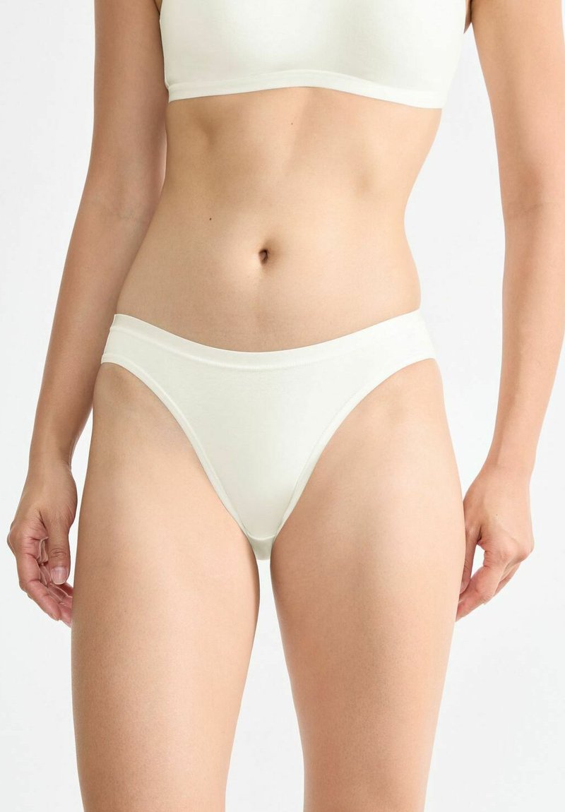 Weißer Baumwoll-Bikini-Unterwäsche mit glatter Textur, niedriger Bundhöhe und einem weichen, breiten Bündchen. Nahtloser Rand und minimaler Schnitt.