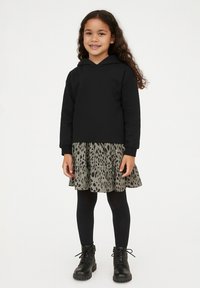 Schwarzer Kapuzenpulli, kombiniert mit einem schichten Graugrün-Kleid mit Leopardenmuster, schwarzen Strumpfhosen und schwarzen Schnür-Stiefeletten.