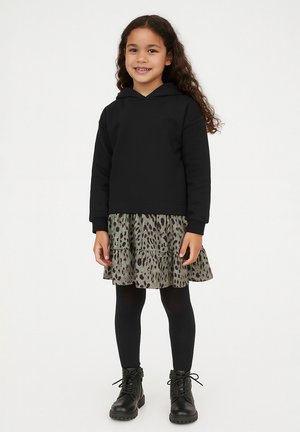 Schwarzer Kapuzenpulli, kombiniert mit einem schichten Graugrün-Kleid mit Leopardenmuster, schwarzen Strumpfhosen und schwarzen Schnür-Stiefeletten.