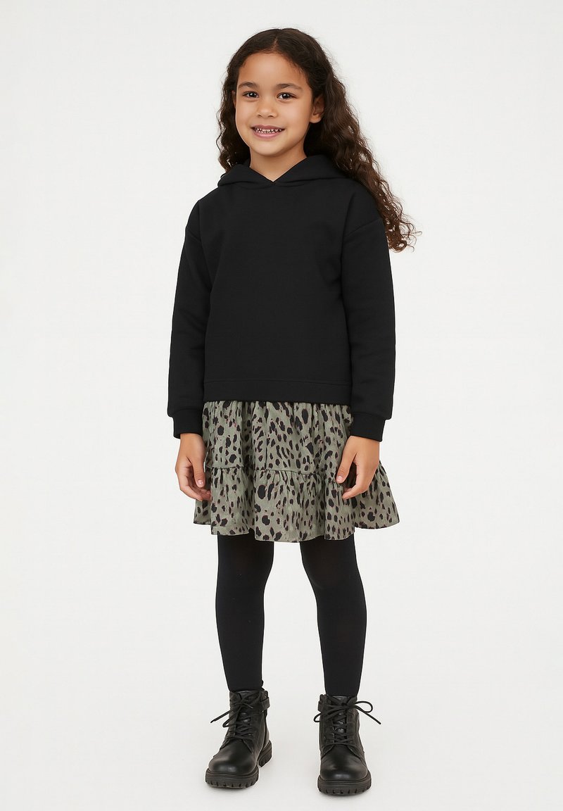 Schwarzer Kapuzenpulli, kombiniert mit einem schichten Graugrün-Kleid mit Leopardenmuster, schwarzen Strumpfhosen und schwarzen Schnür-Stiefeletten.