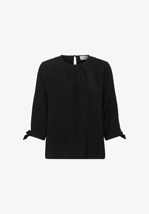 Blouse noire texturée avec des manches 3/4, décolleté rond, fermeture à bouton clé au dos et petits poignets noués.
