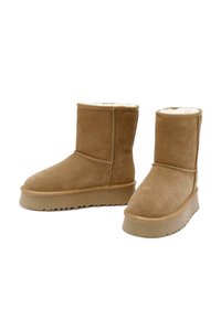 Bottes mi-mollet en daim brun clair avec semelles épaisses en caoutchouc et doublure en polaire blanche visible à l'intérieur, présentées côte à côte sur fond blanc.