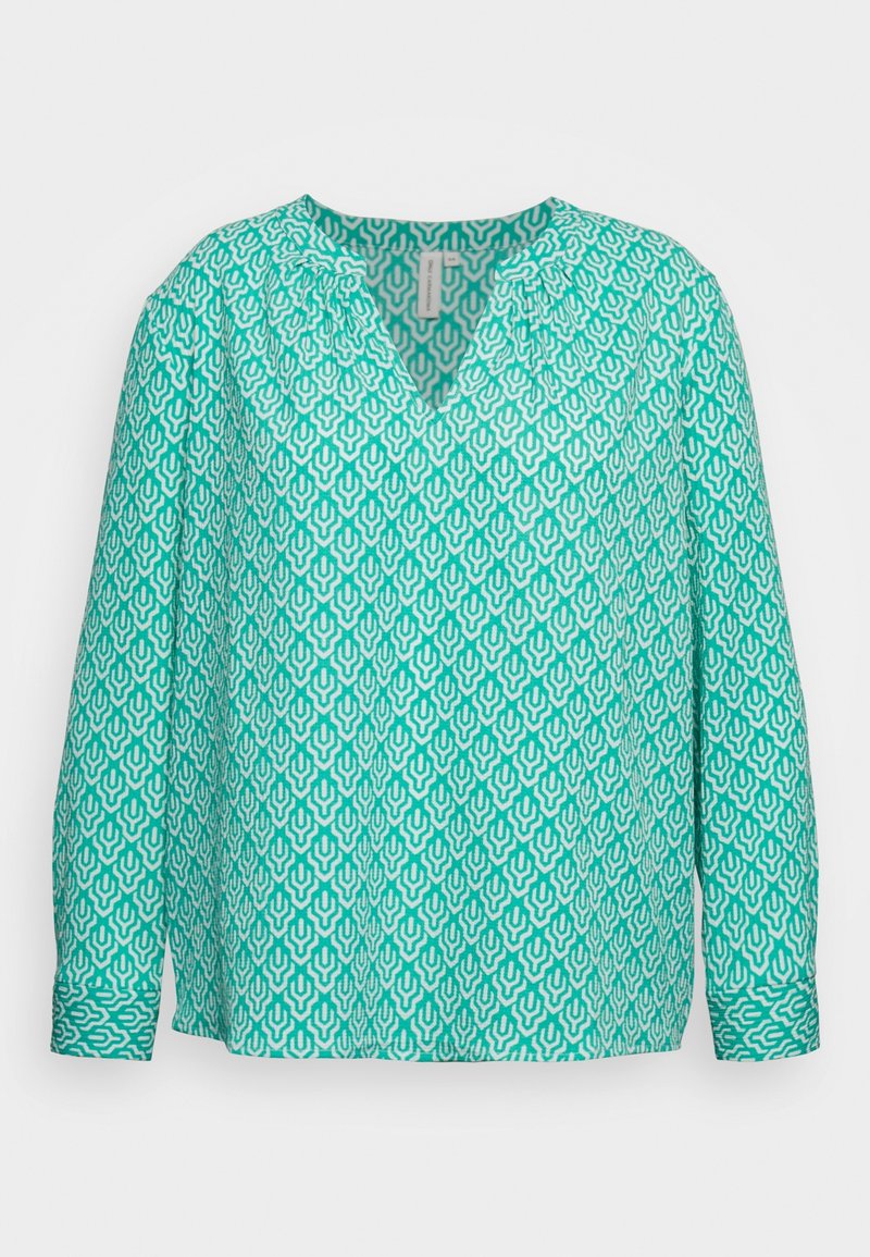 Blouse turquoise à manches longues avec un motif géométrique blanc, décolleté en V et détails froncés aux épaules. Texture de tissu lisse.