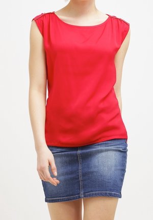 Czerwony top bez rękawów z okrągłym dekoltem i akcentami na ramionach, zestawiony z dopasowaną dżinsową spódnicą. Gładka tekstura, casualowy fason.