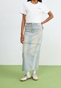 Vaaleansininen farkkukankainen maksihame, jossa vaakasuuntainen kuviollinen yksityiskohta, valkoisilla raidoilla ja korkealla vyötäröllä. Yhdistetty valkoiseen t-paitaan ja lenkkareihin.