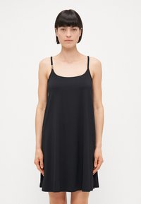 Vestido negro sin mangas hecho de una tela suave, con un escote cuadrado y tirantes ajustables con herrajes decorativos.