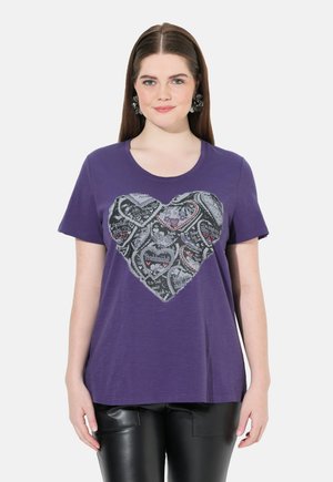 Lilla kortærmet t-shirt med et struktureret hjerte-design i sort og grå, der har forskellige mønstre og tekster i forskellige farver.
