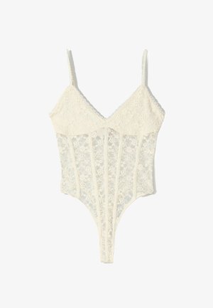 Biały koronkowy body z cienkimi regulowanymi ramiączkami, kwiatowym wzorem, dekoltem w serek i przezroczystymi siateczkowymi detalami na tułowiu.