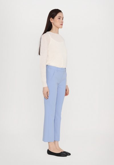 Lightweight cream sweater paired with tailored pastel blue trousers, featuring a mid-rise waist and sleek black flats. Smooth textures and clean lines.