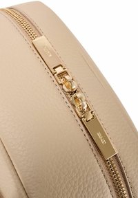 Beżowa, teksturowana skórzana torba z dwoma złotymi suwakami wygrawerowanymi nazwą marki "Céline" na zakrzywionym szwie.