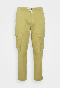 Calças cargo verde oliva claro com cintura elástica e cordão. Possui vários bolsos laterais e pernas ajustadas. Textura de tecido suave.