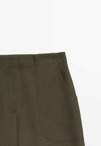 Olijfgroene broek met een gladde textuur, voorzien van twee grote achterzakken en een rechte snit, benadrukt door contrasterende stiksels.