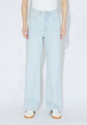 Hellblaue Jeans mit weitem Bein und hoher Taille, Fünf-Taschen-Design und dezentem Verblassen, kombiniert mit weißen Turnschuhen.