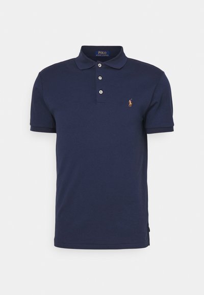 Mornarska polo majica od pamuka, s klasičnim ovratnikom, tri dugmeta i malim logotipom na lijevoj strani prsnog koša. Glatka tekstura.