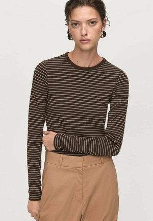 Haut à manches longues marron avec des rayures horizontales blanches, encolure ronde et design ajusté. Associé à un pantalon taille haute beige.