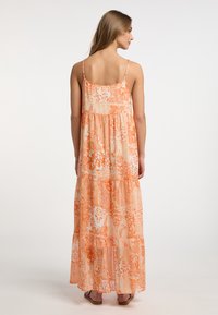 Rochie maxi cu bretele subțiri, având un model floral portocaliu, straturi suprapuse și un material ușor, texturat.
