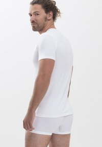 White cotton t-shirt with short sleeves paired with white boxer shorts. Smooth texture, form-fitting design, and minimalistic style.