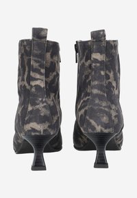 Bottines en daim léopard noir et gris, avec un talon empilé et une fermeture éclair sur le côté. Texture lisse.