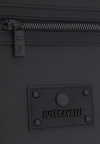 Borsa a tracolla in nylon nero con superficie testurizzata, dotata di una zip superiore e di un'etichetta logo con rivetti per un tocco di dettaglio in più.