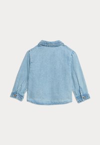 Giacca di jeans azzurra chiara con maniche lunghe, polsini con bottoni e colletto. Presenta un orlo cucito e una vestibilità rilassata. Vista posteriore.