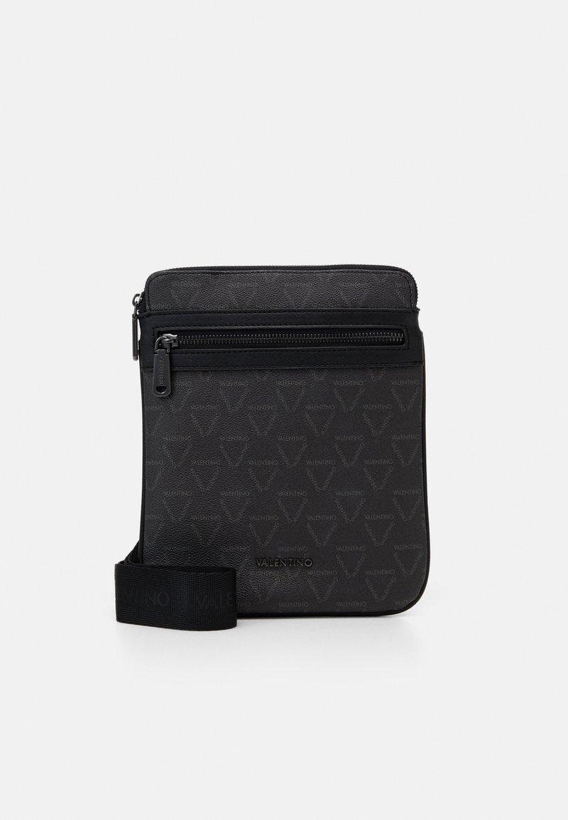 Sac bandoulière noir avec une surface texturée, doté d'une fermeture éclair, d'une sangle ajustable et d'un motif de logo subtil. Fini lisse.