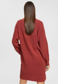 Abito lavorato a maglia lungo con maniche, di colore maroon, dal taglio rilassato e con colletto. Il tessuto presenta un motivo a trama, che arriva poco sopra le cosce.