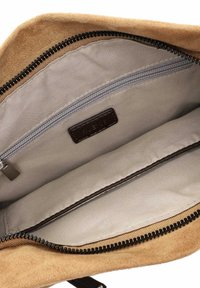 Tanfarbene Wildledertasche mit einem Reißverschlussfach, beige gefüttert und einem braunen Lederetikett. Ausgestattet mit einem schwarzen Reißverschluss für sicheren Verschluss.