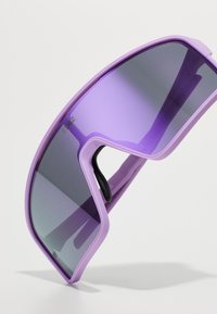 Lunettes de sport violettes avec un design enveloppant, dotées de verres teintés foncés et d'une monture légère. Coussinets de nez réglables pour un confort optimal.