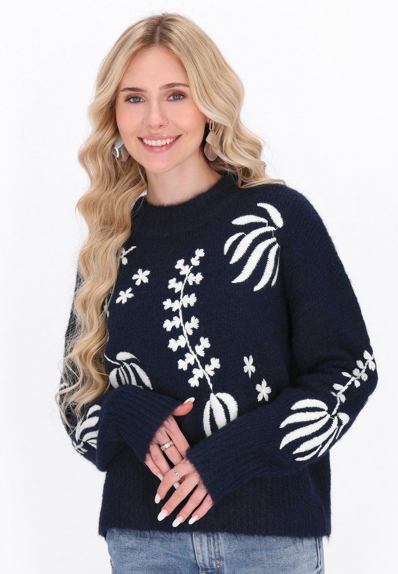 Marineblauer Strickpullover mit weißer Blumenstickerei, Rundhalsausschnitt und gerippten Bündchen. Weicher Stoff und lässige Passform.