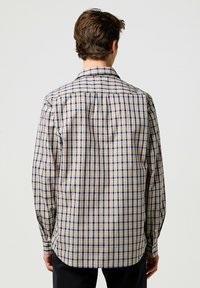 Heren overhemd met lange mouwen in een crème, blauw en rood geruit patroon. Knop-down kraag, knoppenmanchetten en een afgeronde zoom met een losse pasvorm.