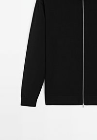 Maglione nero con zip, maniche e orlo a costine. Presenta una texture liscia e una cerniera metallica con linguetta. Design semplice e minimalista.