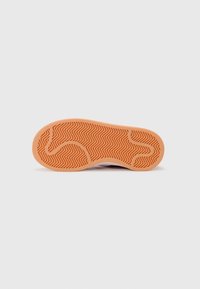 Sneaker sole with patterned herringbone texture in orange rubber, featuring grooves for traction. Clean, minimal design with no visible branding.